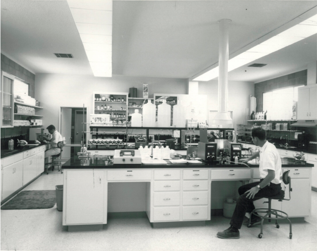 Black and white picture of founder of Dellavalle Laboratories, Nat Dellavalle, working in lab